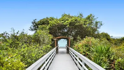 a boardwalk leading to a tunnel in the middle of a forest at One Seagrove Place 0207 in Santa Rosa Beach