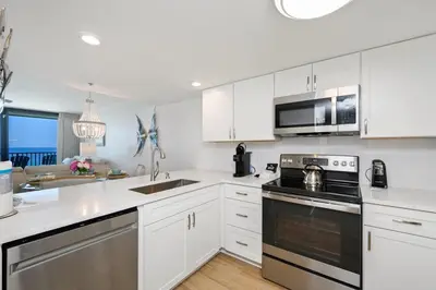 a kitchen with white cabinets and stainless steel appliances at One Seagrove Place 1204 in Santa Rosa Beach