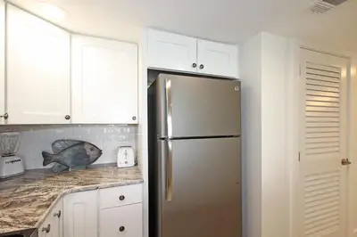 a kitchen with a stainless steel refrigerator and white cabinets at One Seagrove Place 0208 in Santa Rosa Beach