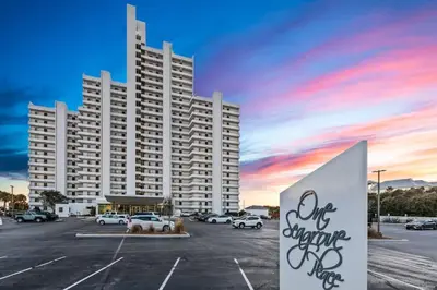 a large white building with a parking lot with cars at One Seagrove Place 0208 in Santa Rosa Beach