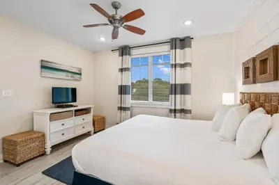 a bedroom with a white bed and a television at SunDune on 30A in Santa Rosa Beach
