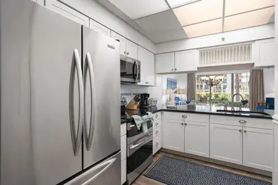 a kitchen with white cabinets and a stainless steel refrigerator at High Pointe Resort 131 in Inlet Beach