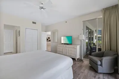 a white bedroom with a large bed and a chair at High Pointe Resort 131 in Inlet Beach