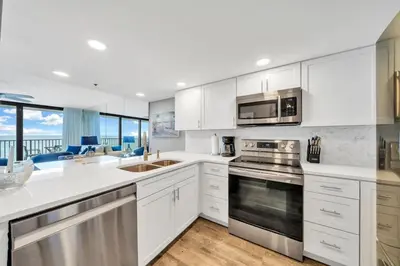 a kitchen with white cabinets and stainless steel appliances at One Seagrove Place 0402 in Santa Rosa Beach