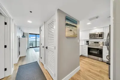 a kitchen with white cabinets and a door leading into a hallway at One Seagrove Place 0402 in Santa Rosa Beach