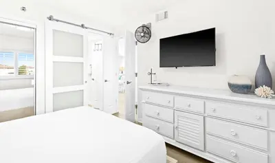 a white bedroom with a white dresser and a tv at One Seagrove Place 0406 in Santa Rosa Beach