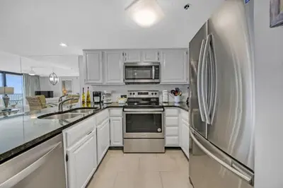 a kitchen with white cabinets and a stainless steel refrigerator at One Seagrove Place 1603 in Santa Rosa Beach