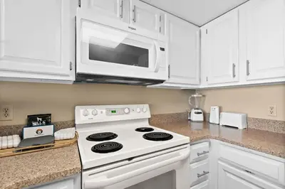 a white kitchen with a stove and a microwave at One Seagrove Place 2106 in Santa Rosa Beach