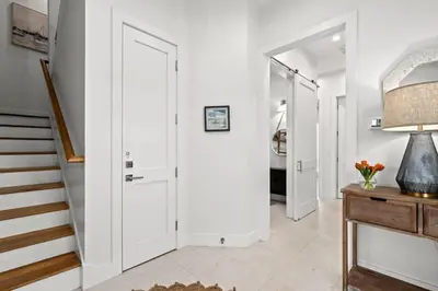 a hallway with white walls and a door and stairs at Laguna Loafin' in Panama City Beach