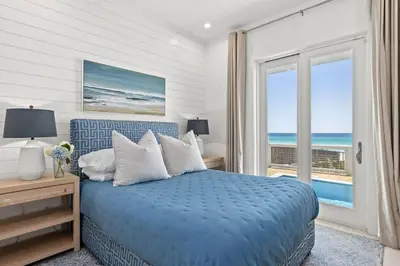 a bedroom with a blue bed with a view of the ocean at Laguna Loafin' in Panama City Beach
