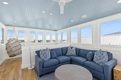 a living room with a blue couch and windows at Laguna Loafin' in Panama City Beach