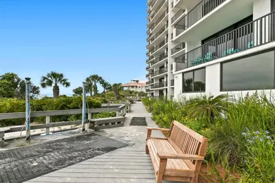 a wooden bench sitting on a walkway next to a building at One Seagrove Place 0408 in Santa Rosa Beach
