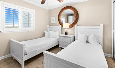 two beds in a bedroom with a mirror and a window at One Seagrove Place 1606 in Santa Rosa Beach