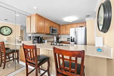 a kitchen with wooden cabinets and a counter with chairs at One Seagrove Place 1606 in Santa Rosa Beach