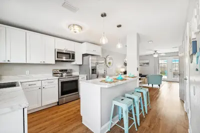 a kitchen with white cabinets and a kitchen island with stools at Coastal Retreat by the Beach in Panama City Beach