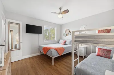 a bedroom with two bunk beds and a flat screen tv at Coastal Retreat by the Beach in Panama City Beach