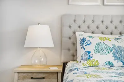 a lamp on a night stand next to a bed at Coastal Retreat by the Beach in Panama City Beach