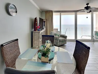 a dining room with a table and chairs with a view at Emerald Beach #1333 in Panama City Beach