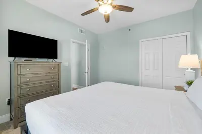 a white bedroom with a bed and a flat screen tv at Laketown Wharf #1510 in Panama City Beach