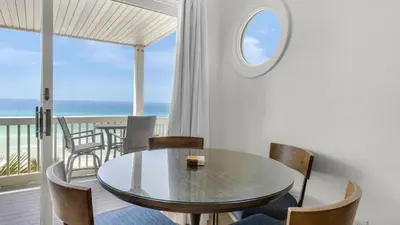 a dining room with a table and chairs and the ocean at Mistral 12 in Seacrest