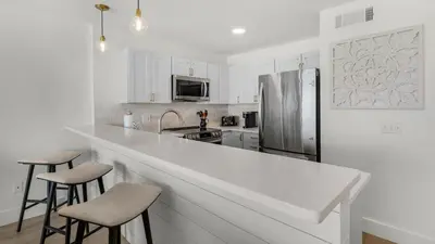 a white kitchen with a large counter and stools at Mistral 12 in Seacrest