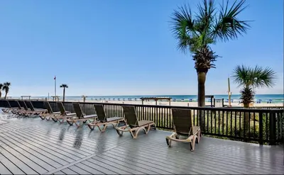 a row of chairs on a boardwalk next to the beach at Newly Completely Renovated Beach Condo at Sunbird Resort! Free Beach Chair and Umbrella Service! by Dolce Vita Getaways! in Panama City Beach