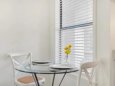 a glass table with two chairs and a yellow bird on it at Charming Beach Studio With Pool & Sauna in Panama City Beach