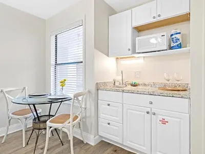 a kitchen with white cabinets and a table and chairs at Charming Beach Studio With Pool & Sauna in Panama City Beach
