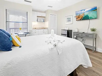 a white bedroom with a large white bed with at Charming Beach Studio With Pool & Sauna in Panama City Beach