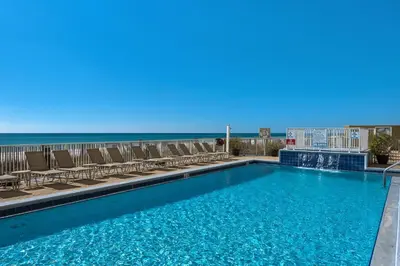 a swimming pool with chairs and the ocean in the background at Emerald Isle 1504 in Panama City Beach