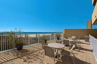 a patio with tables and chairs and the beach at Emerald Isle 1504 in Panama City Beach