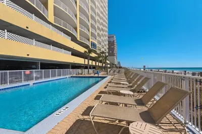 a swimming pool with chaise lounge chairs next to a building at Emerald Isle 1504 in Panama City Beach
