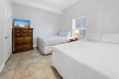 a white bedroom with two beds and a dresser at Ocean Villa 2004 by Emerald Coast Retreats Unit in Panama City Beach
