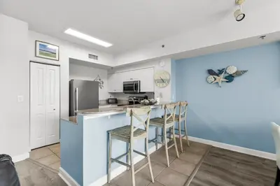 a kitchen with a counter and two stools at Stylish 1BD Beachfront Condo with Amenities Galore! by Dolce Vita Getaways! in Panama City Beach