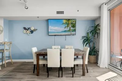 a dining room with a table and white chairs at Stylish 1BD Beachfront Condo with Amenities Galore! by Dolce Vita Getaways! in Panama City Beach