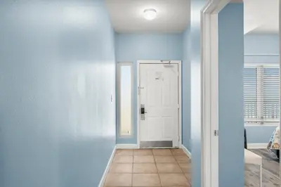a hallway with blue walls and a white door at Stylish 1BD Beachfront Condo with Amenities Galore! by Dolce Vita Getaways! in Panama City Beach