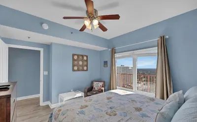 a bedroom with blue walls and a ceiling fan at Stylish 1BD Beachfront Condo with Amenities Galore! by Dolce Vita Getaways! in Panama City Beach