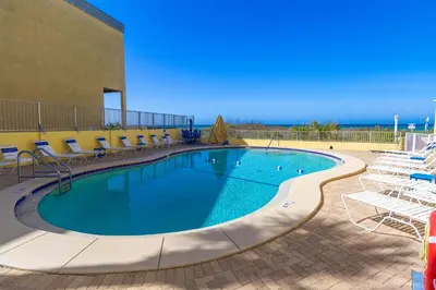 a swimming pool with chairs and the ocean in the background at K and J Panama City Beach in Panama City Beach