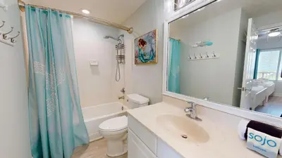 a bathroom with a sink and a toilet and a mirror at Tidewater 1005 in Panama City Beach