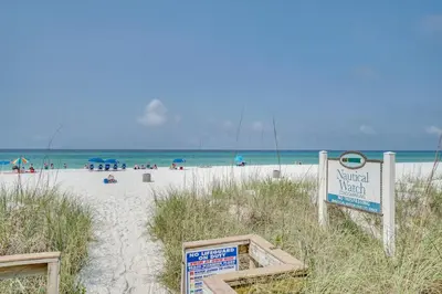 a sign on a beach with people on the beach at Nautical Watch #E-7 by Book That Condo in Panama City Beach