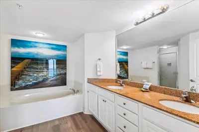 a bathroom with two sinks and a bathtub and a painting at 601 Grandview East in Panama City Beach