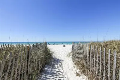 a fence on a beach with the ocean in the background at 203 Moondrifter in Panama City Beach