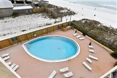 a swimming pool with lounge chairs and the beach at 203 Moondrifter in Panama City Beach