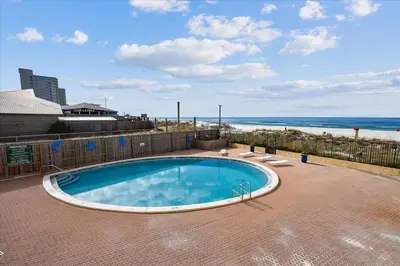 a swimming pool with the beach in the background at 203 Moondrifter in Panama City Beach