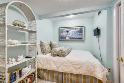 a bedroom with a bed and a book shelf at 203 Moondrifter in Panama City Beach