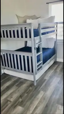 two white bunk beds in a room with wood floors at A Shore Thing- A in Panama City Beach