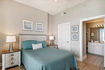a bedroom with a blue bed and a bathroom at 2102 Ocean Villa in Panama City Beach