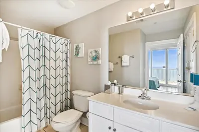 a bathroom with a toilet and a sink and a mirror at 2102 Ocean Villa in Panama City Beach