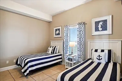 two beds in a room with a window at 2102 Ocean Villa in Panama City Beach