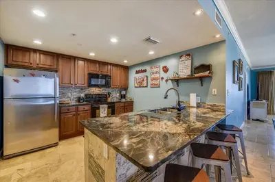 a kitchen with a stainless steel refrigerator and wooden cabinets at 1909 Seychelles in Panama City Beach